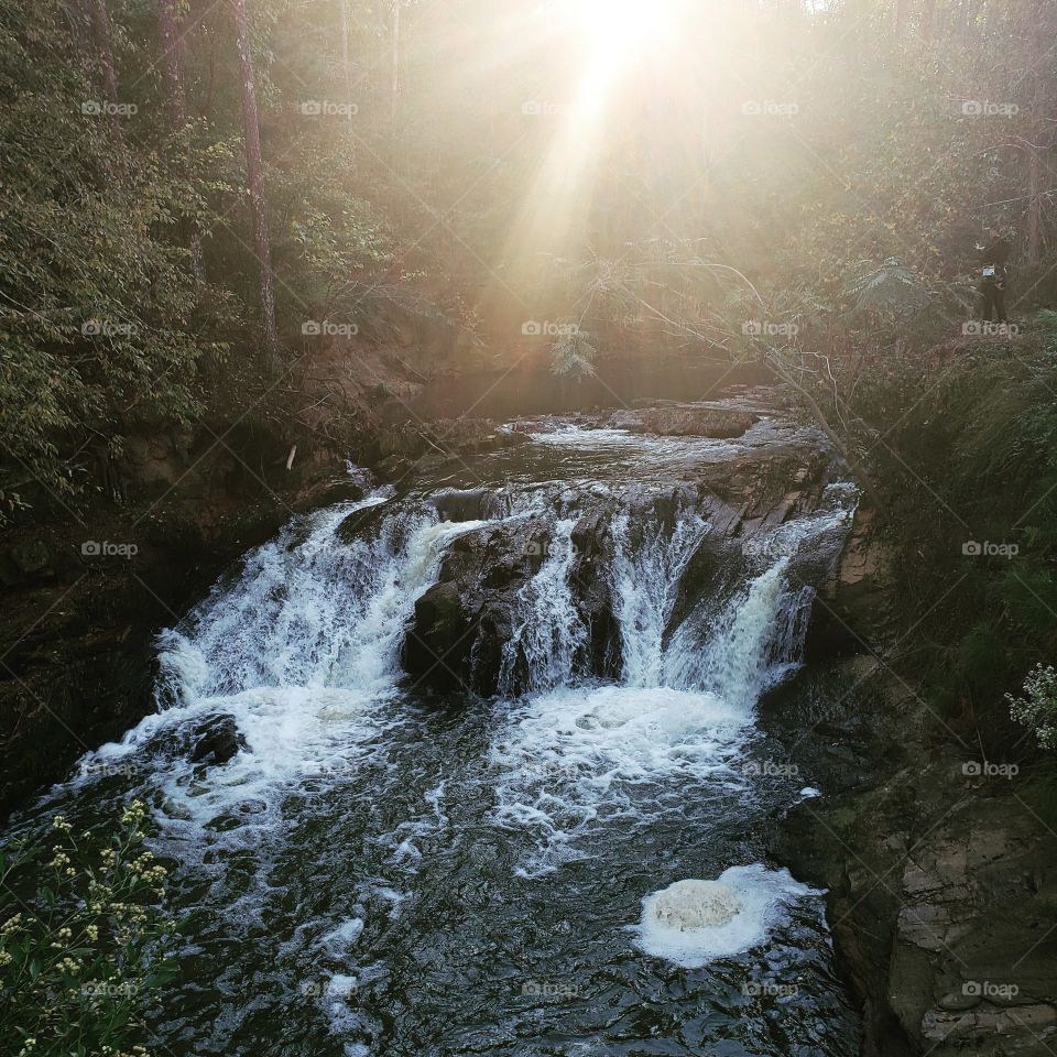 sun shining on small waterfall