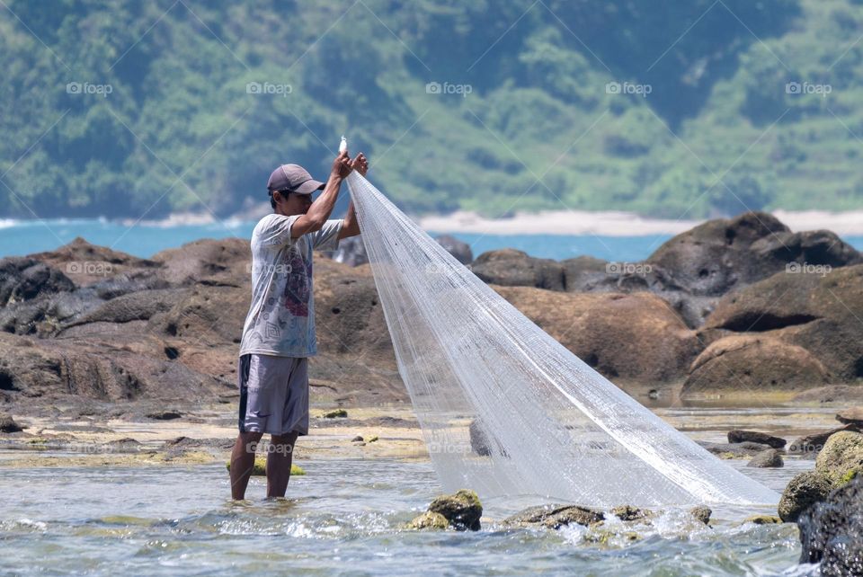 fisherman fishing on the beach in a polka dot t-shirt