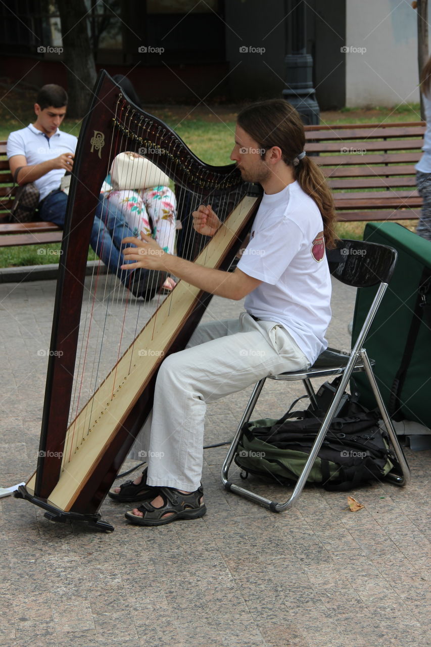 мужчина играет на арфе на Арбате в Москве