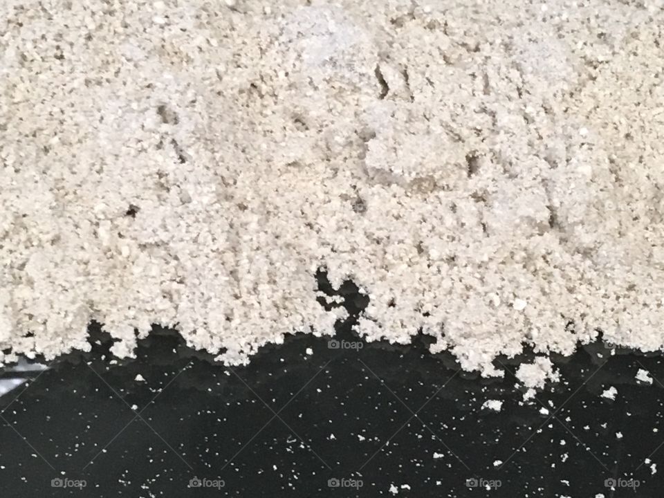White grains of sand or pebbles in a empty fish tank against black bottom