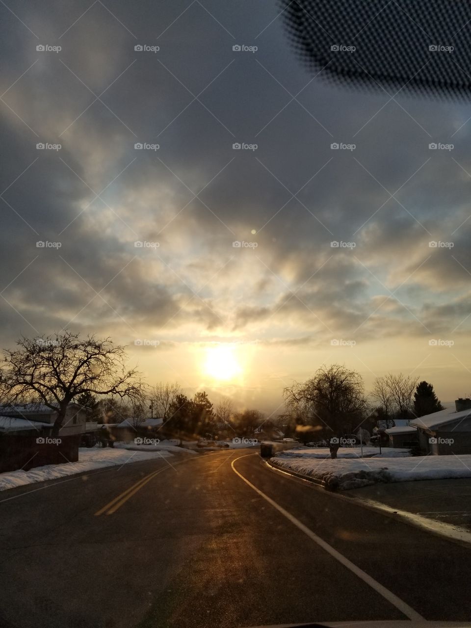 Here is one of my favorite sunset photos from my gallery. As the sun sets and falls behind the mountains of the west it leaves a mark of beauty for an eye to see here we have the clouds, the road, houses, trees and the sun. there is beauty all around