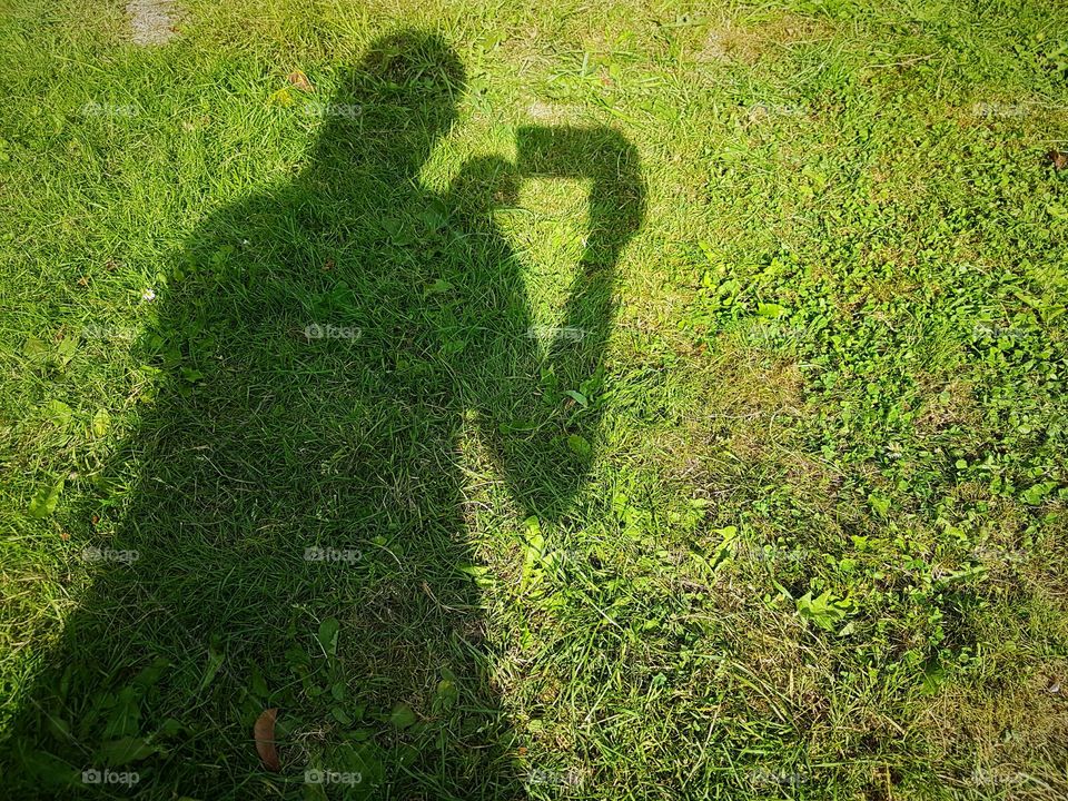 Shadow of a woman with mobile on the grass
