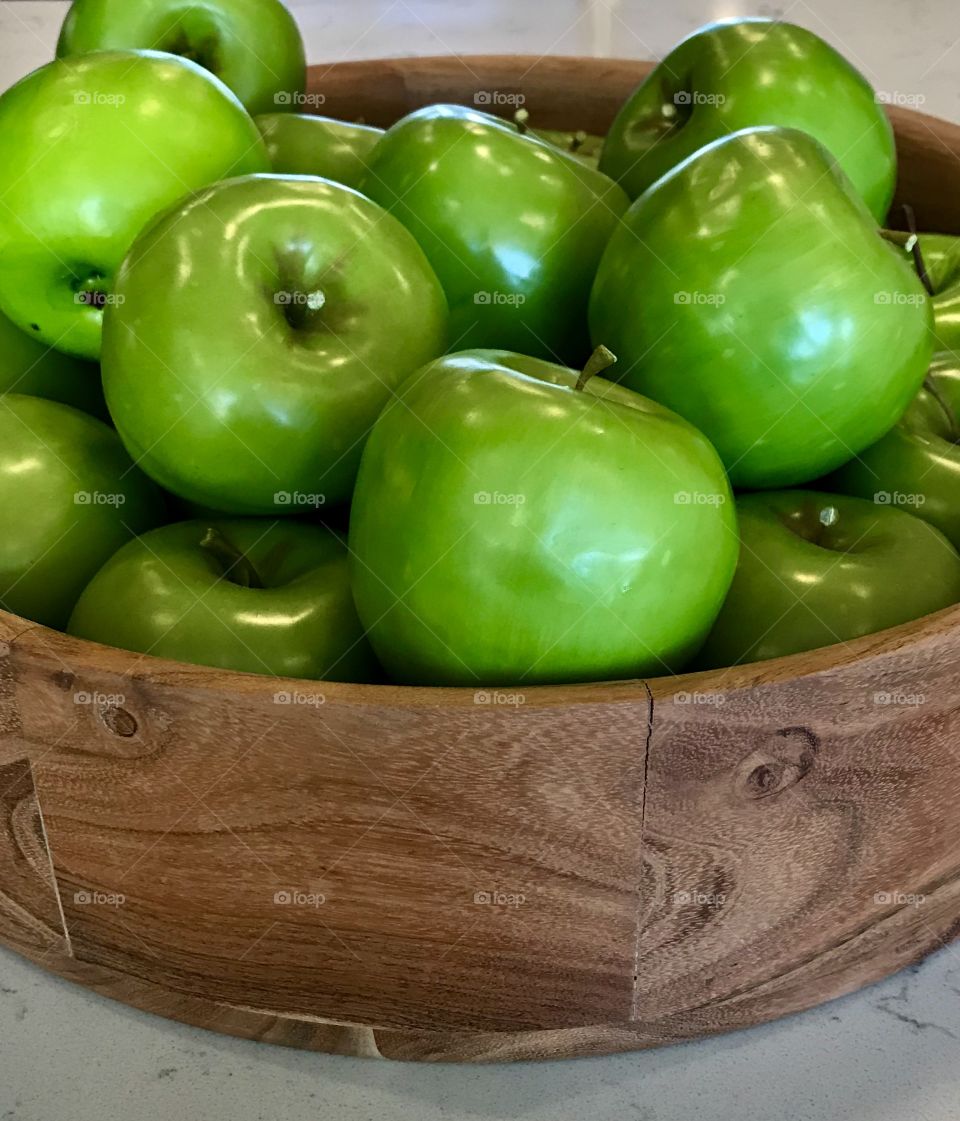 Shiny tasty green apple in a wooden bowl