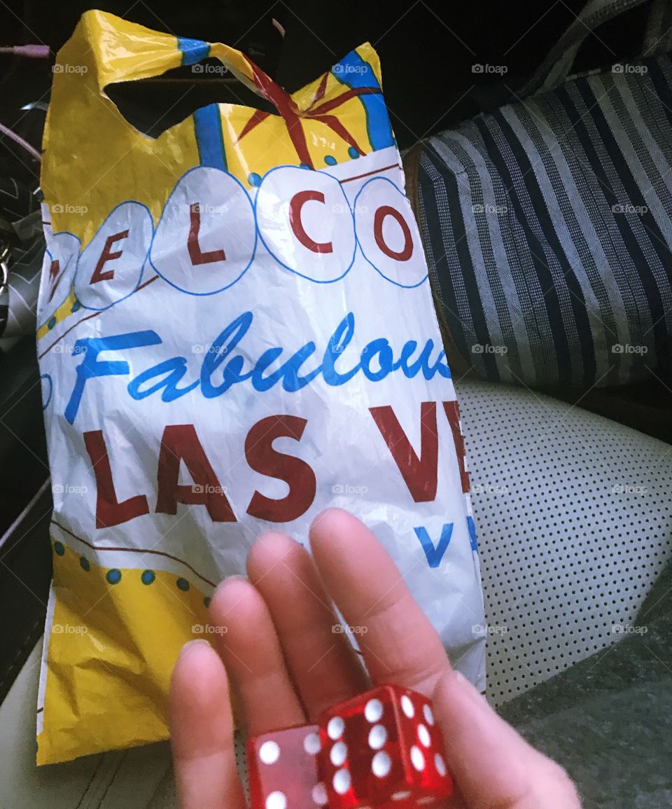 A woman holding a pair of dice in front of a welcome to fabulous Las Vegas NV gift bag. USA, America 