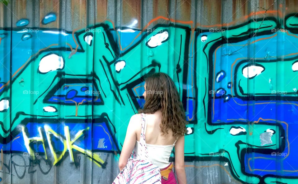 Girl in front of graffiti.