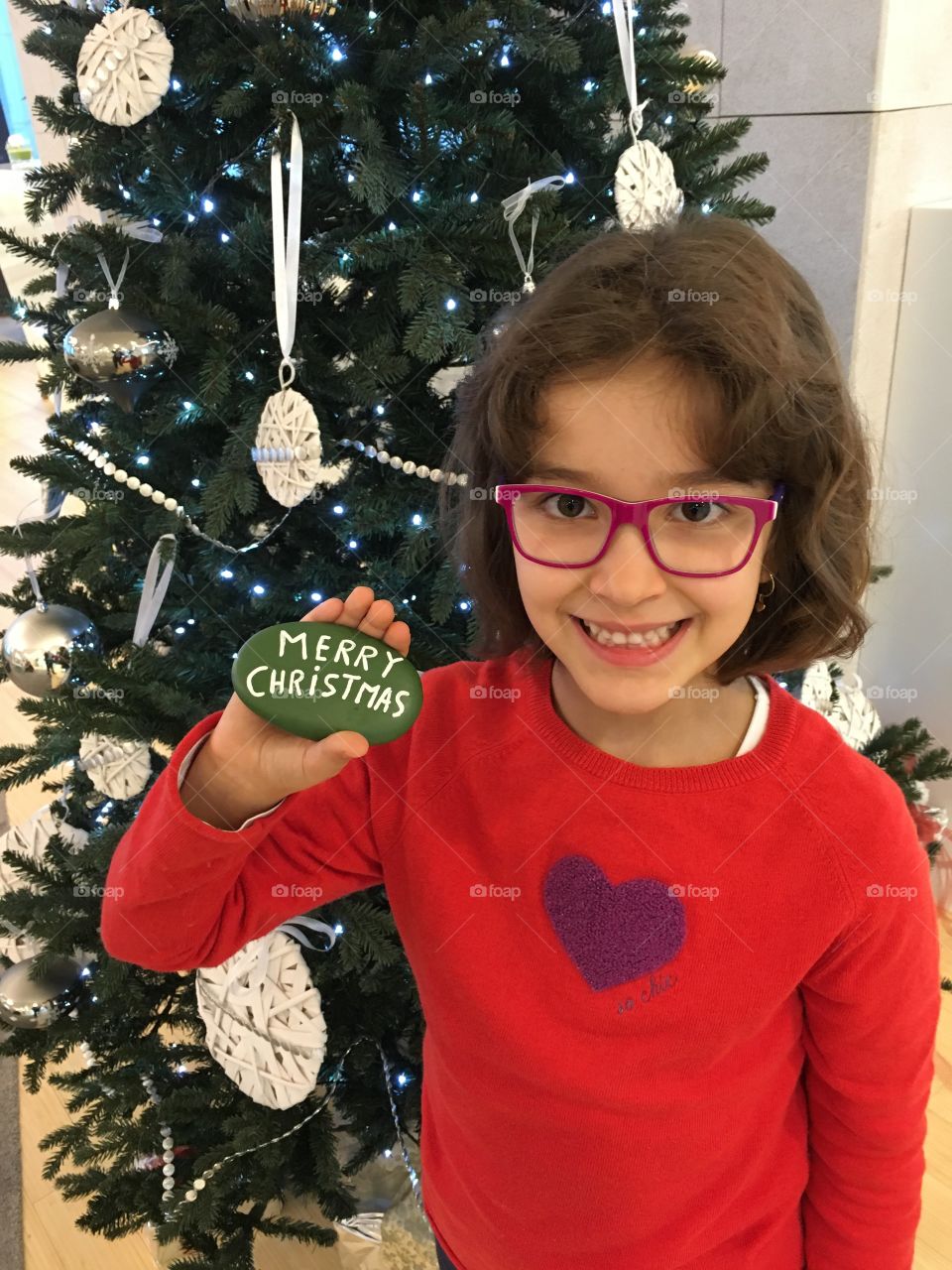 Girl showing pebble stone merry christmas word