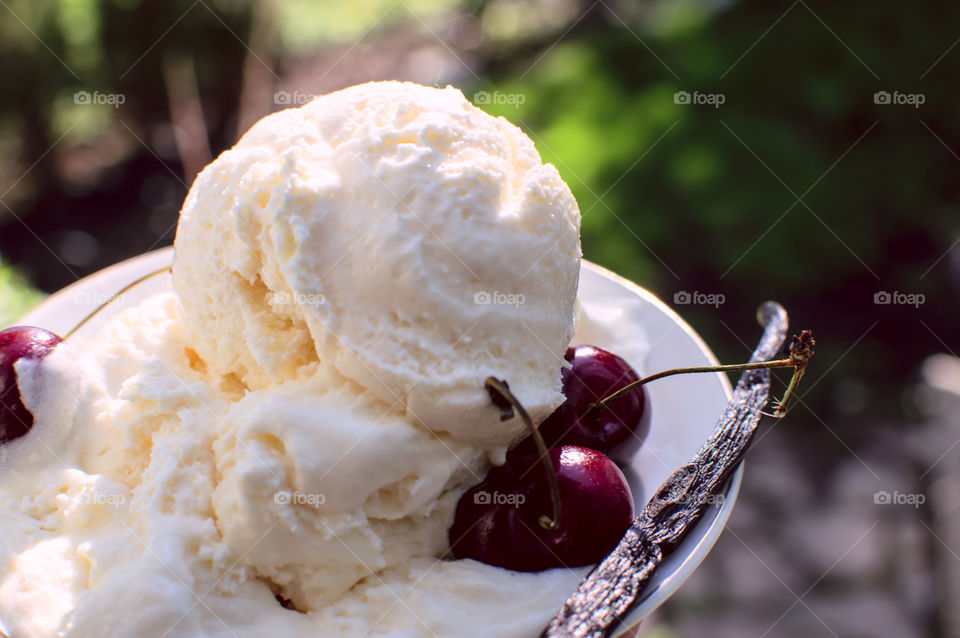 Vanilla ice cream on plate with cherry and plant pod
