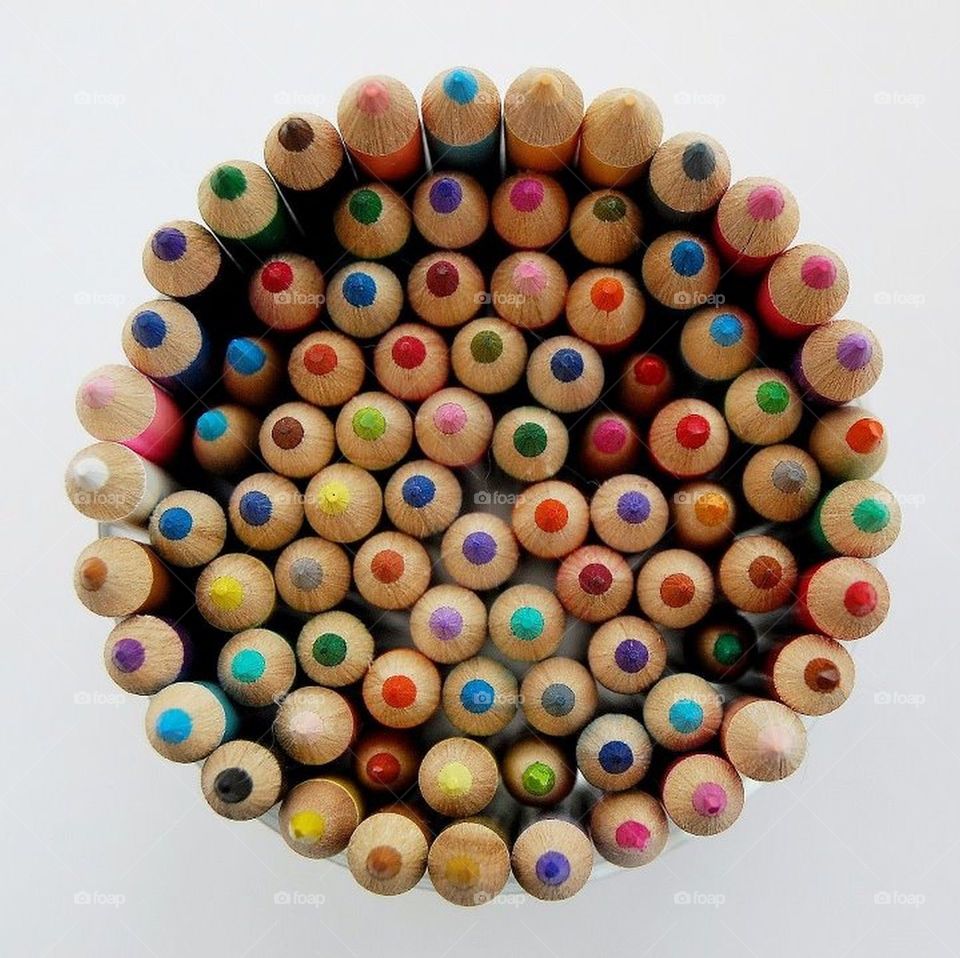 Lots of different coloured crayons arranged in a circle with points upwards. 