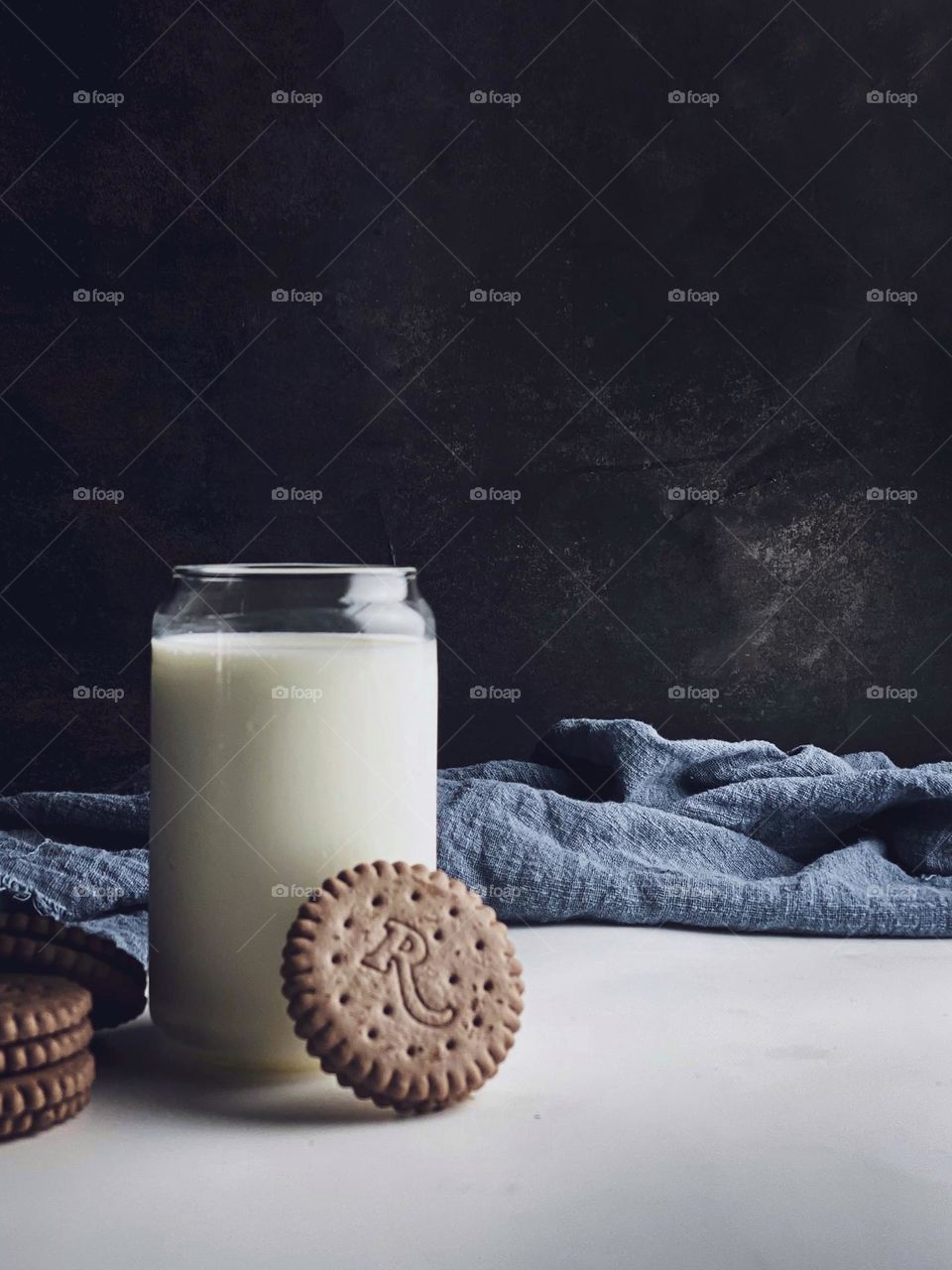 A dish of fresh milk in a glass with cookies on the table.