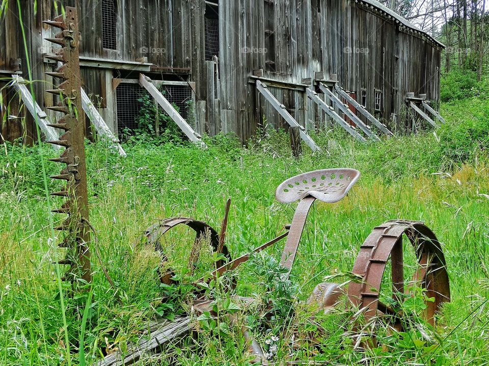 Rustic Old Farm Equipment. Vintage Plow And Antique Barn In Old West Ghost Town
