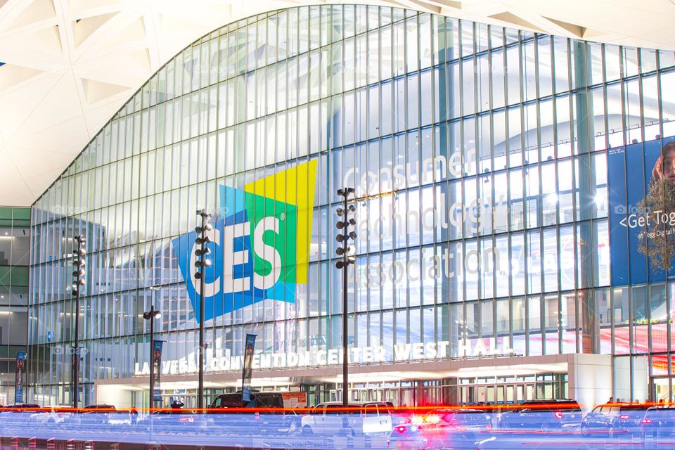 Las Vegas, NV, USA 1-6-2023: Exterior of Convention Center West Hall during CES2023. Logo of CES on glass wall. Light trails from car headlights of traffic passing by. Captured in long exposure.