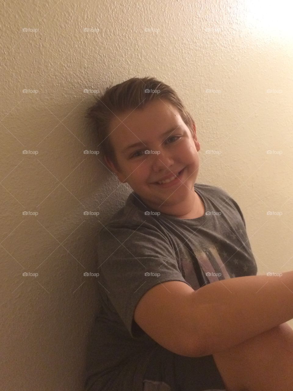 Portrait of smiling little boy sitting against wall