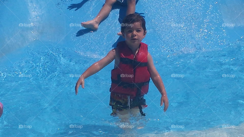 Little boy standing in swimming pool