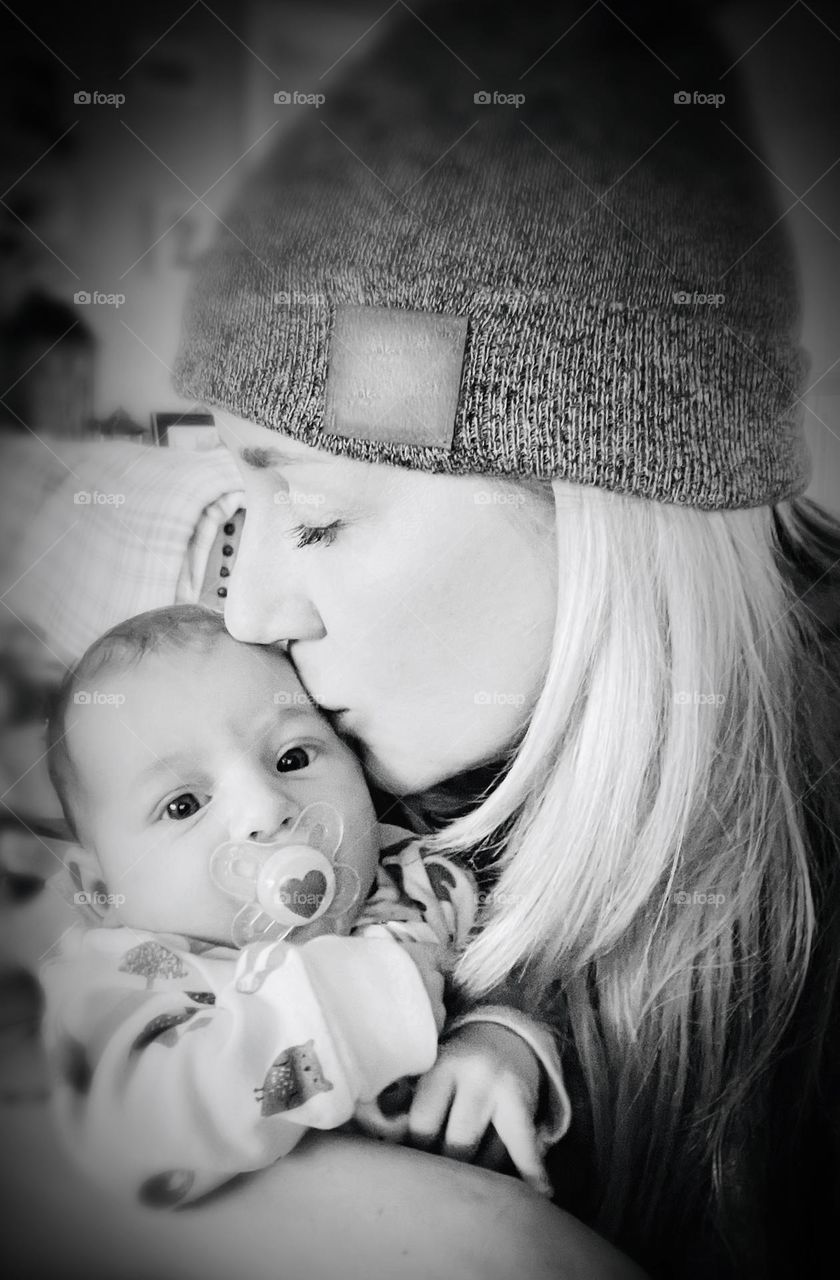 A newborn receives a loving kiss from her grandmother after arriving for a family visit