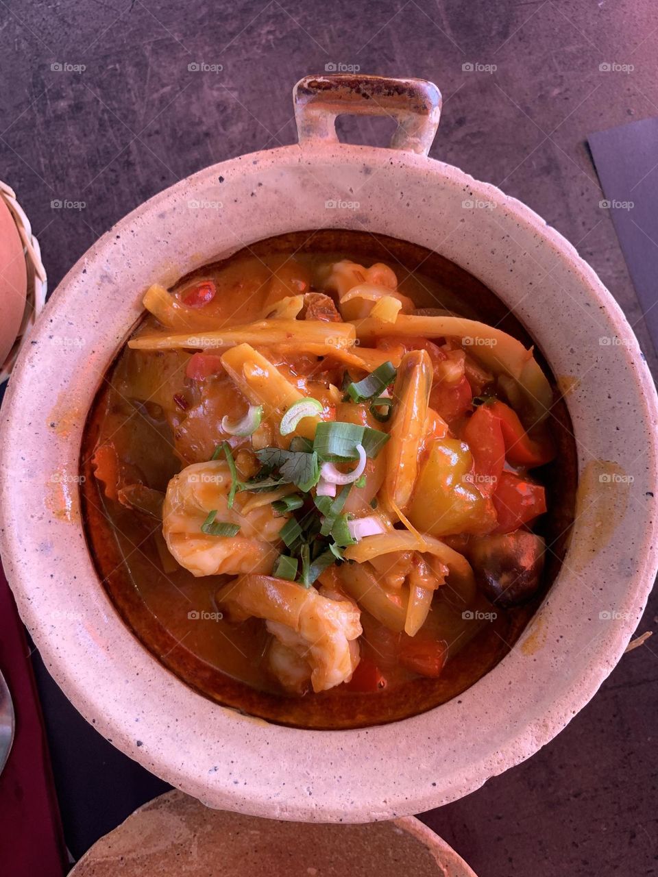 Red curry shrimps and fresh spring onion served in clay pots, Thai cuisine 