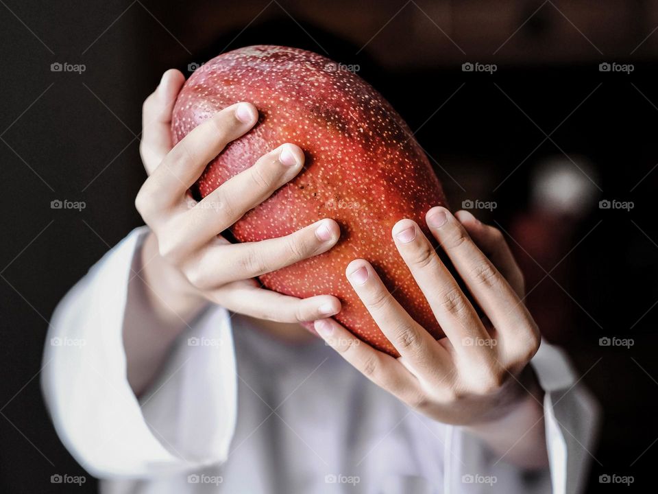 Close-up view of a man holding the red japanese  mango