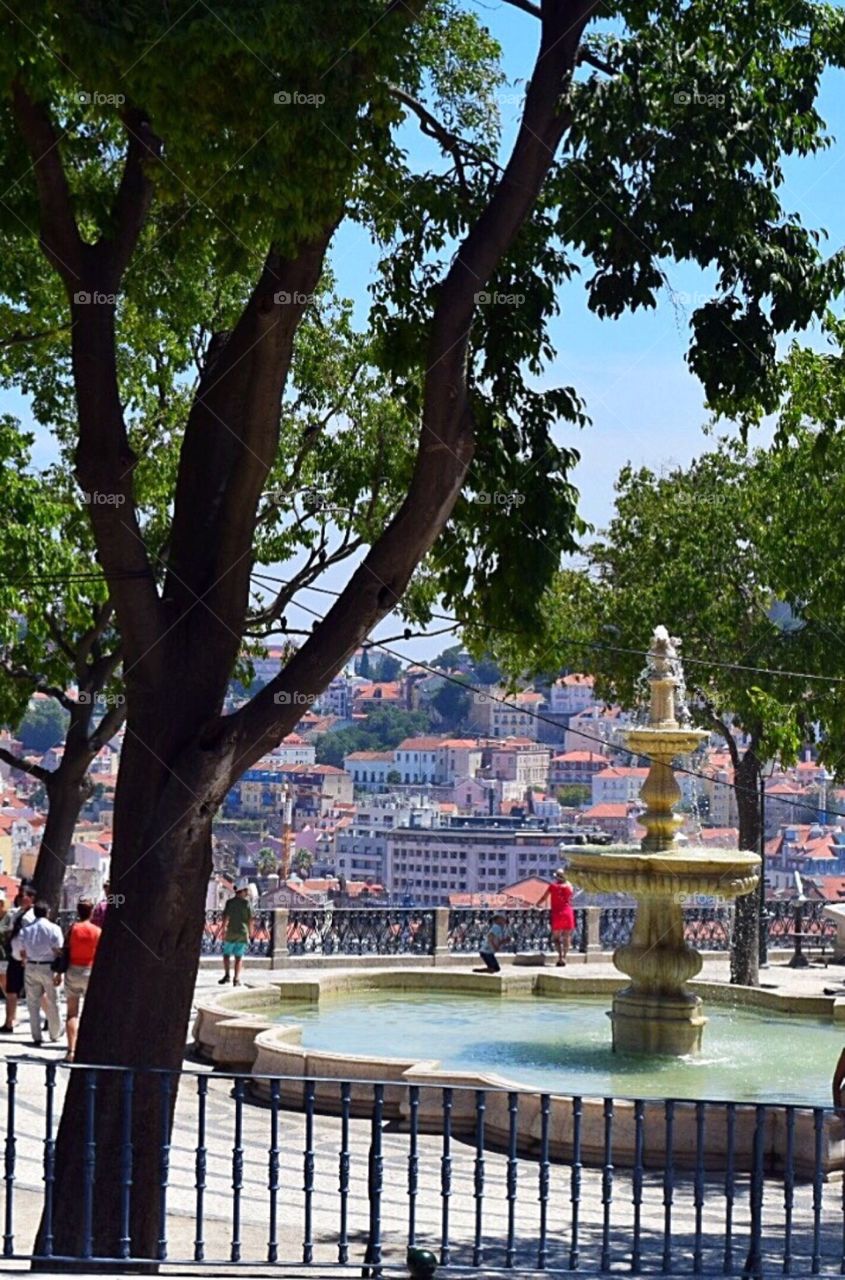 People enjoying the breathtaking view from the top of the park in Lisbon where it overlooks the city 