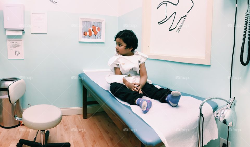 Small little girl sitting on bed in clinic