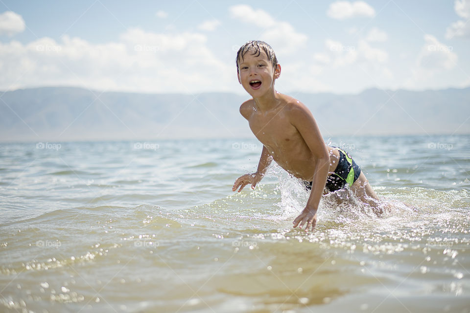 Shirtless boy swimming in sea