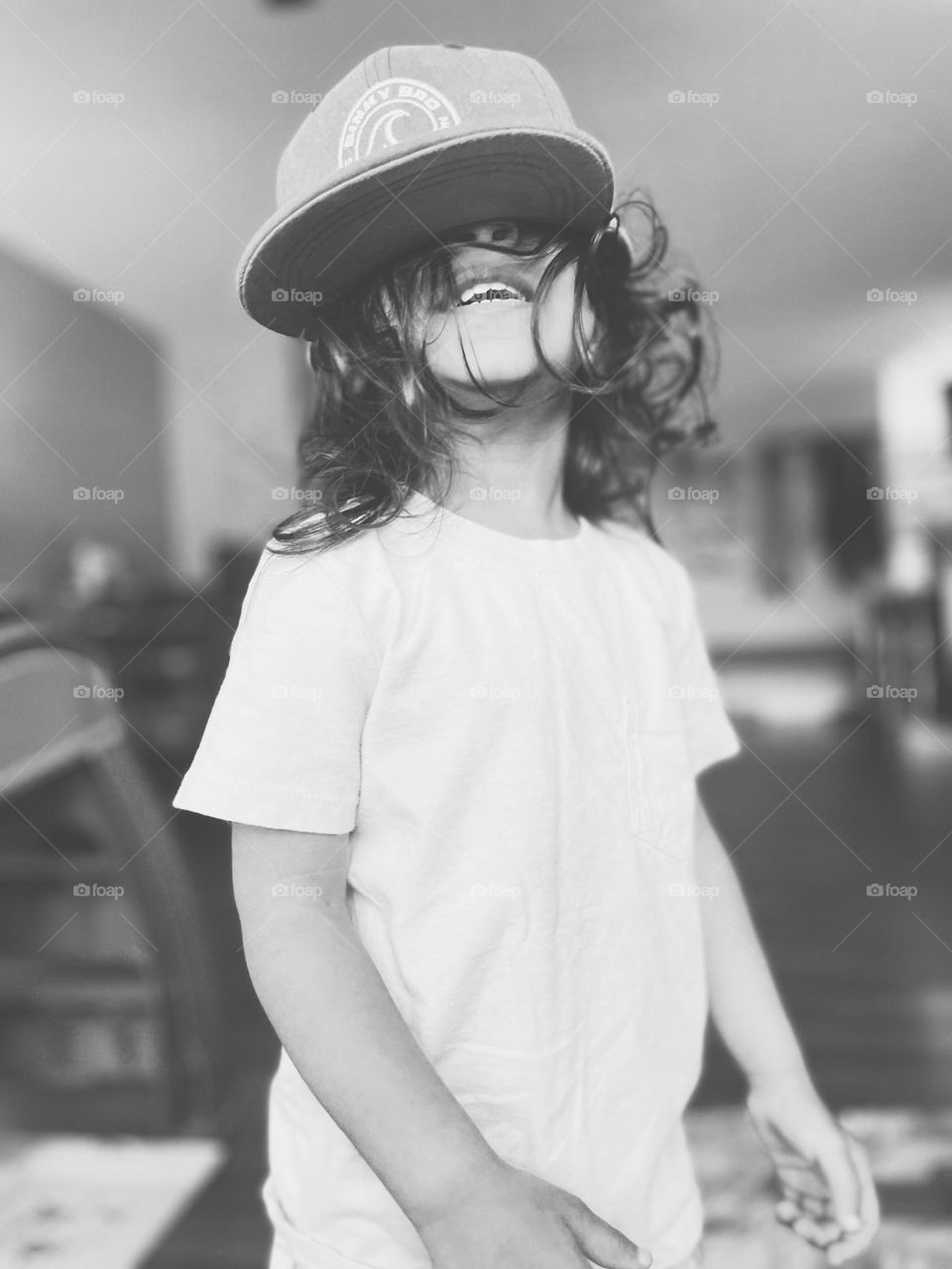 Toddler girl acts silly, toddler has fun with hat, the joy of children, black and white portrait of a child 