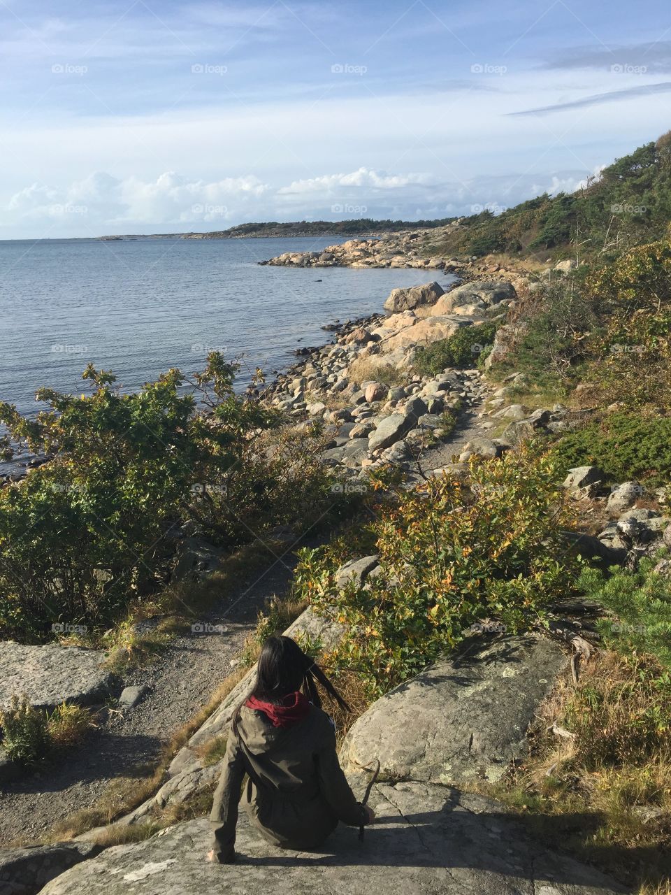 Stony seascape, girl with her back against camera