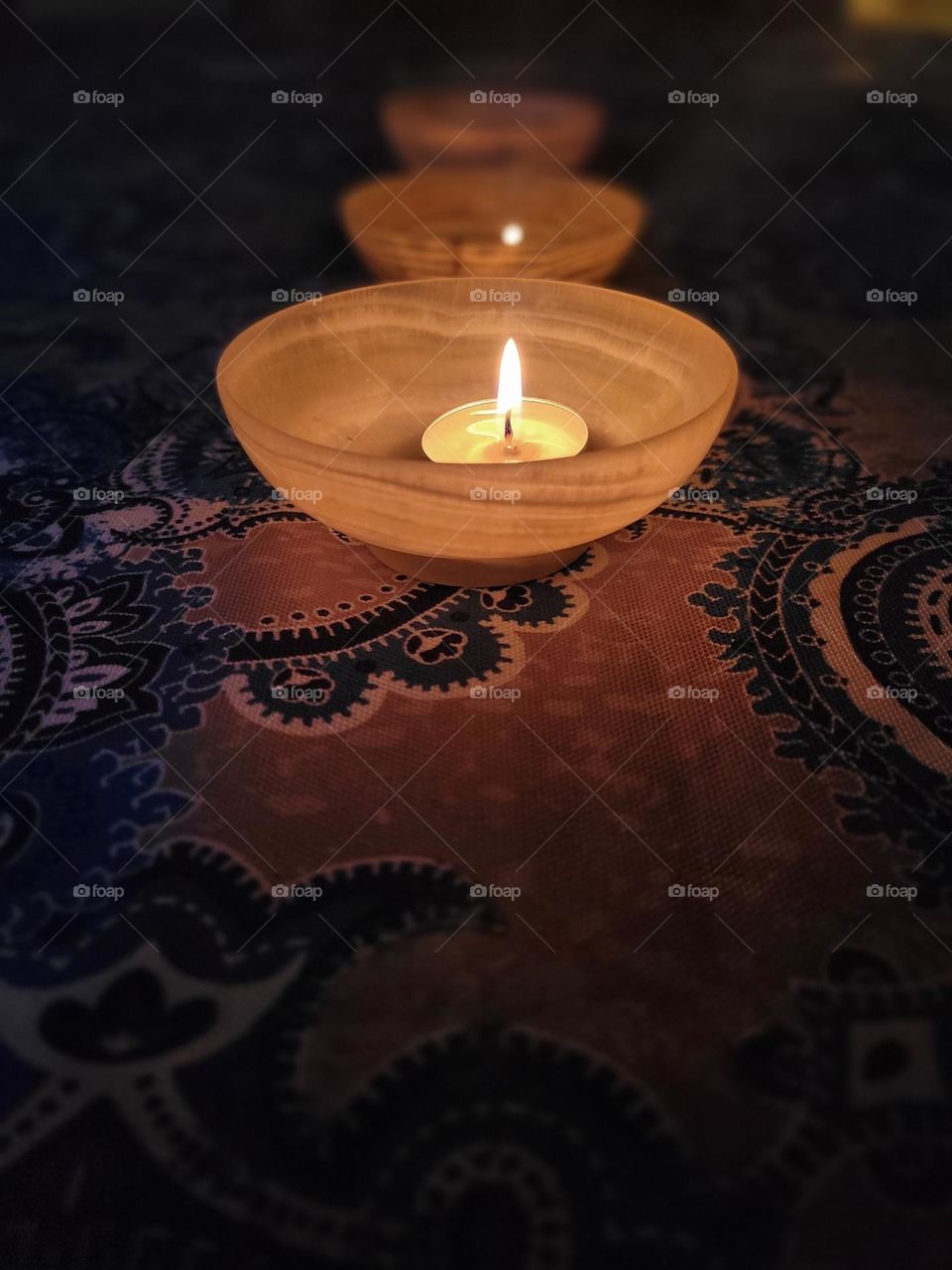 Candle in dark on blue patterned tablecloth