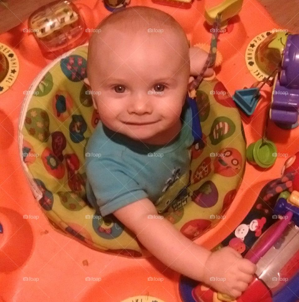 Baby smiling face in his exer-saucer.