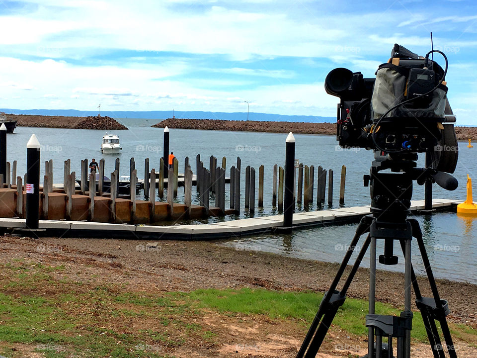 Television Film camera on tripod overlooking Marina as sports fishing boats return from a fishing derby to weigh in their catch