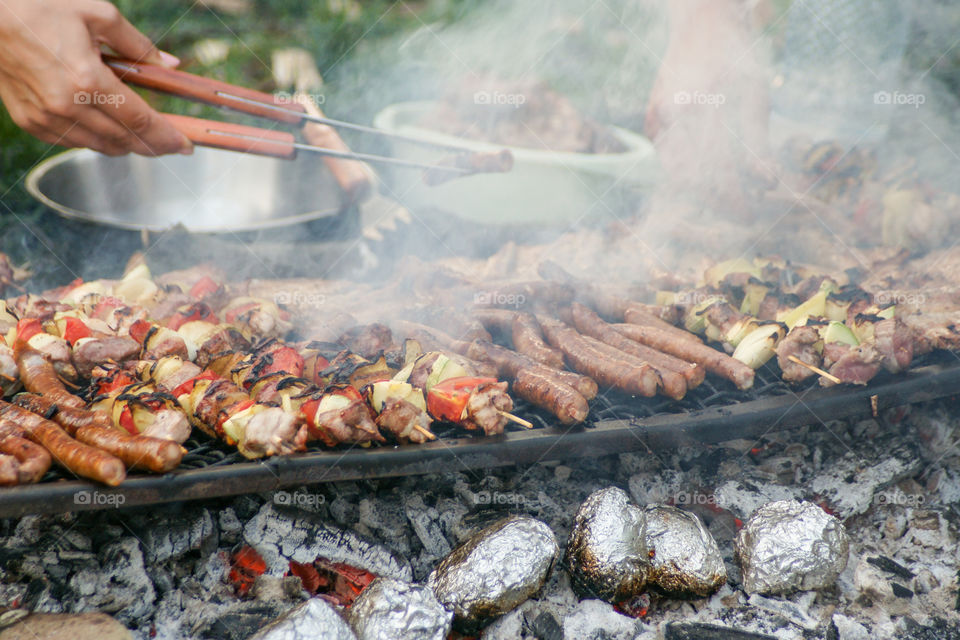 Person roasting meat on barbecue grill