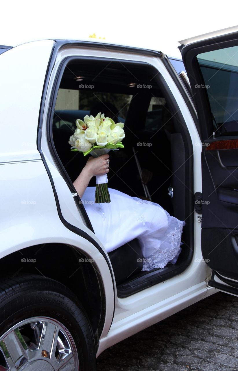 A bride holding her bouquet exiting a limo