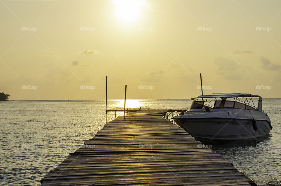 Speed boats moored at the wooden bridge in the sea and Golden reflections of the Sun