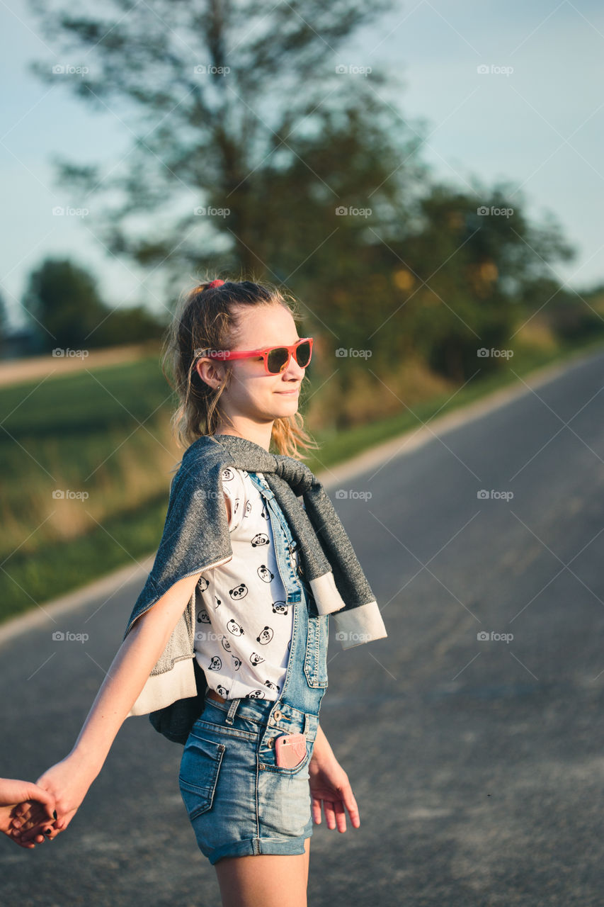 Teenage smiling happy girls having fun walking outdoors, hanging, spending time together on summer day. Real people, authentic situations