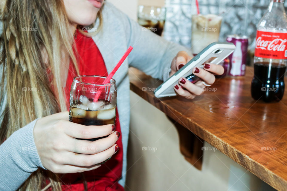 Coke classic- girl on phone while drinking a CocaCola.