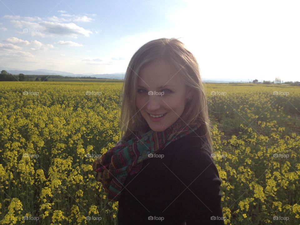 Smiling girl in the field with yellow flowers