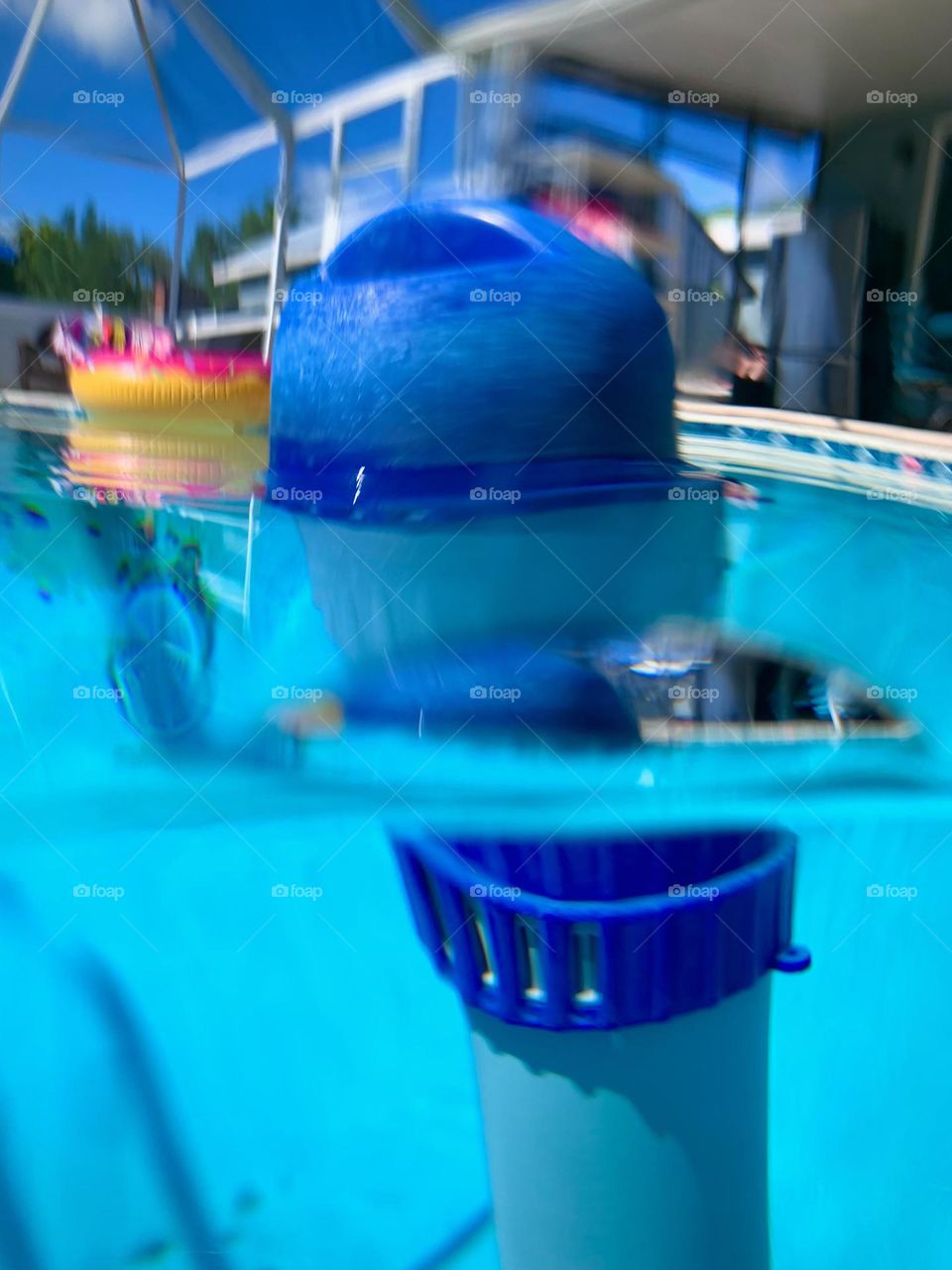 Underwater Chlorine Distributor Blue Floater In Pool Seing Under And Above The Water Under The Blue Sky.