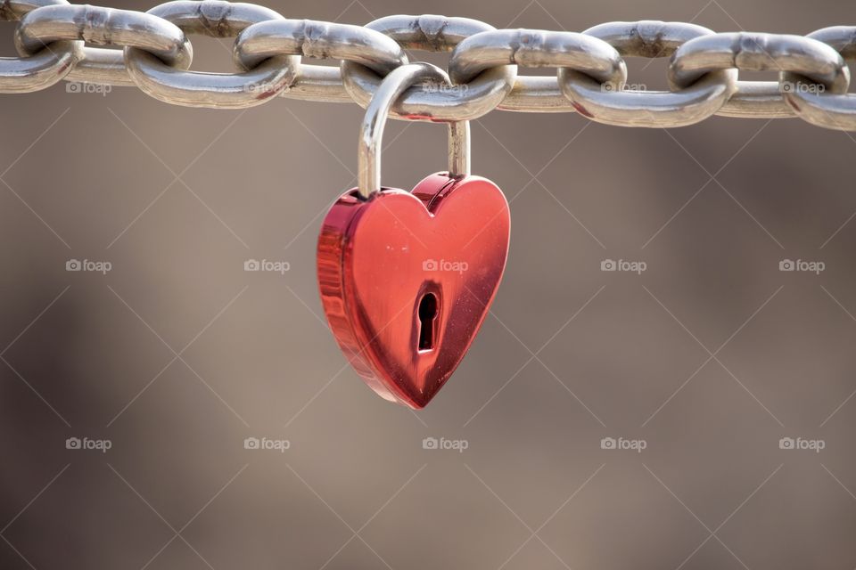 Love, red heart shaped padlock hanging on a metal chain  - Kärlek, rött hänglås format som ett hjärta hänger på en kedja av metall 