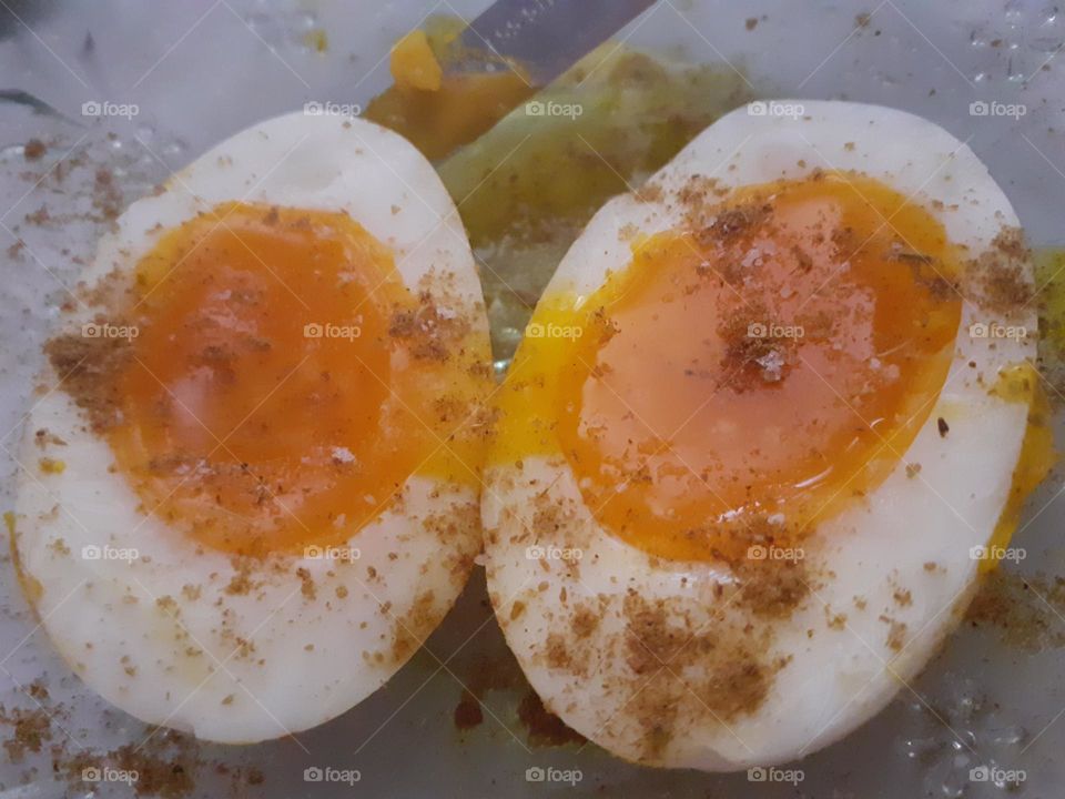 Boiled Eggs. The egg yolks are a vibrant, golden-orange color, indicating that they have been cooked to the ideal consistency. The egg whites have a smooth, firm texture, and are lightly seasoned with what appears to be salt and cumin.