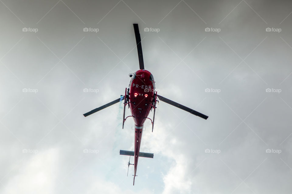helicopter in red in the sky flying low