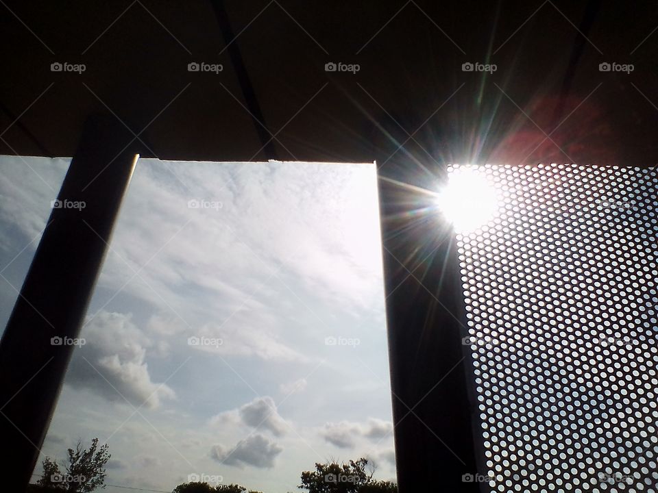 Sunlight penetrates a parapet made of small wire mesh in a park in Jakarta