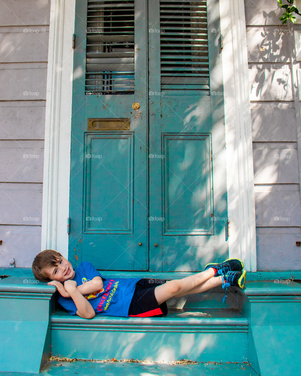Young boy relaxing on the steps of a New Orleans shotgun house 