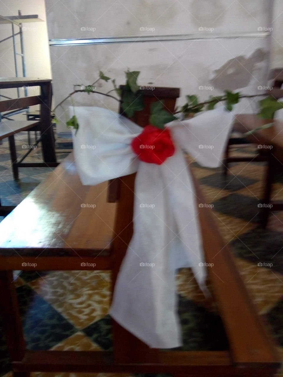 arreglo con flor y moño de tela blanca decorando un banco de madera de la capilla de mi pueblo para la boda cristiana que se realizó hace unos días