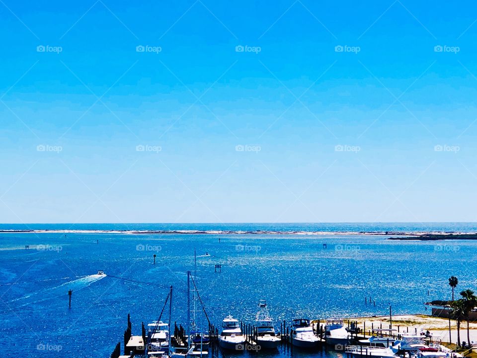 High angle view of motor boats and sail boats in blue water under. Blue sky