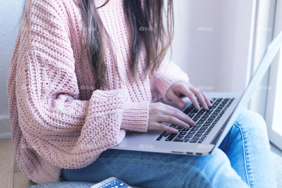 A woman wearing a cozy sweater and using laptop 