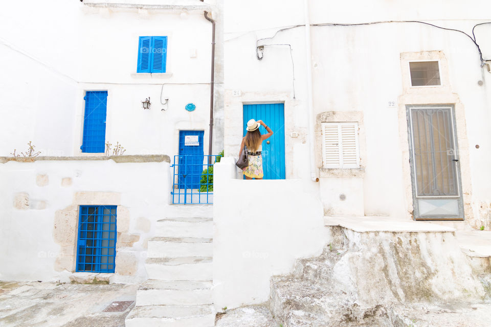 Rear view of a woman standing in front of blue door