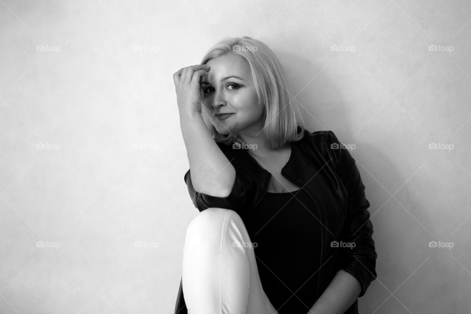 A blonde girl on a white background in a black leather jacket expresses her emotions and feelings (joy, sadness, amorousness, femininity, sensuality, tenderness)