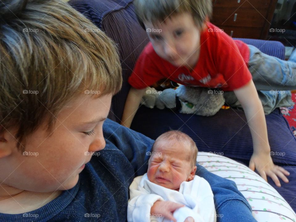 Young Brothers Holding Their Newborn Baby Sister
