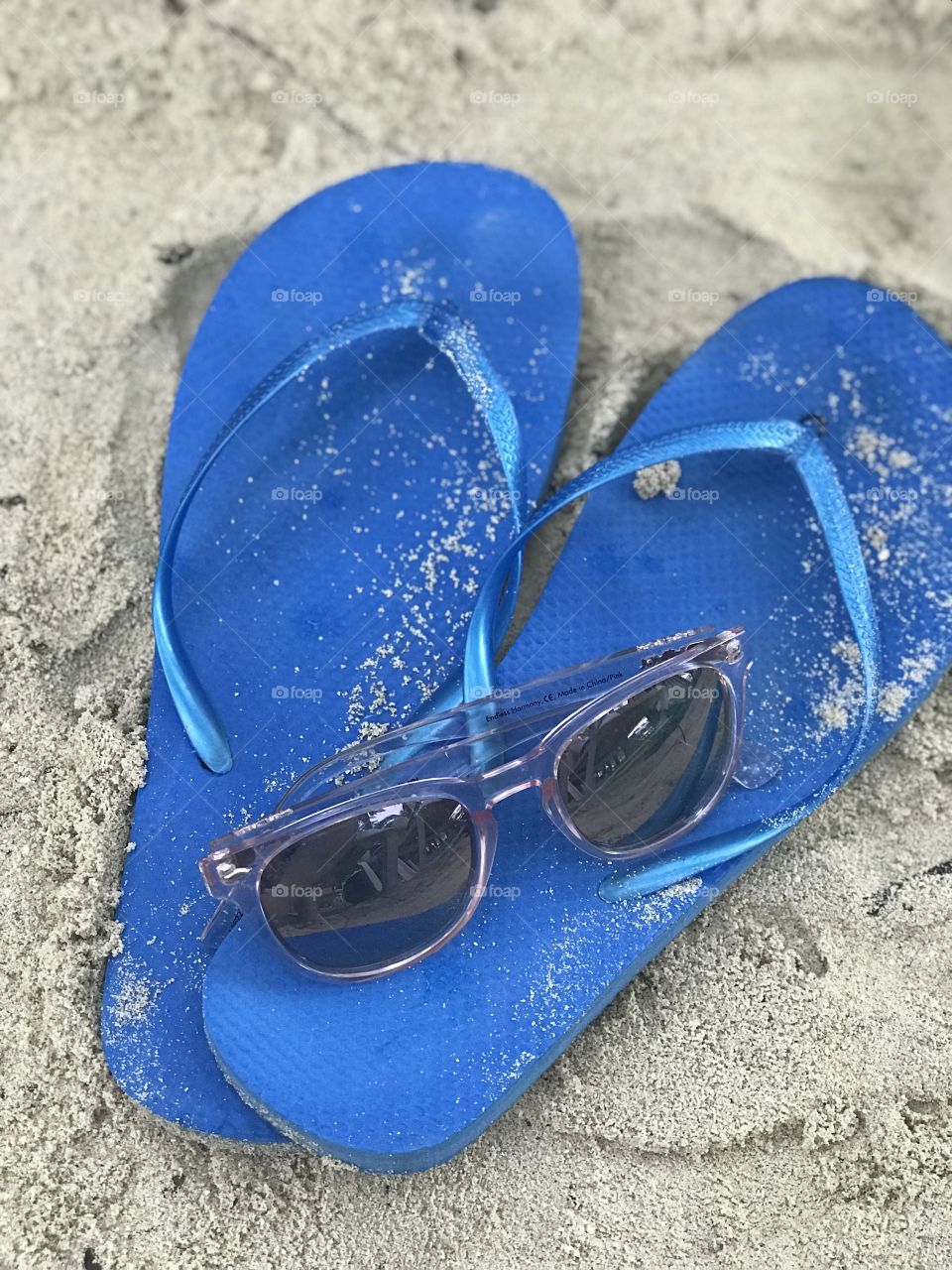 Photo of sandy flip flops and sunglasses from a beach vacation in Honduras. 