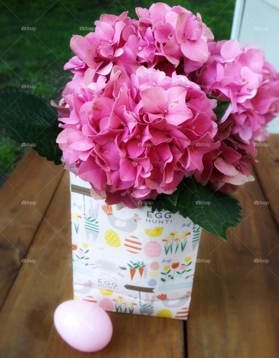 Pink hydrangea in an Easter sack with an Easter egg outside on a patio
