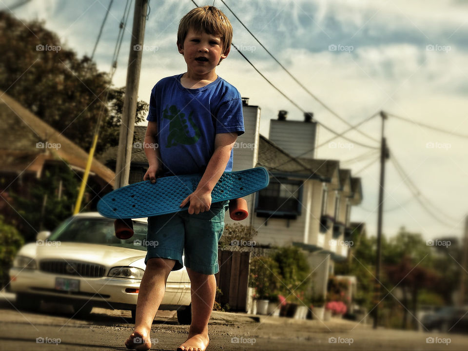 Young boy in neighborhood holding a skateboard