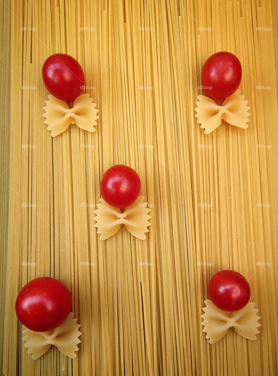 Composition. Food. "Capellini" pasta has red cherry tomatoes with "Farfalle" pasta in the shape of a bow tie